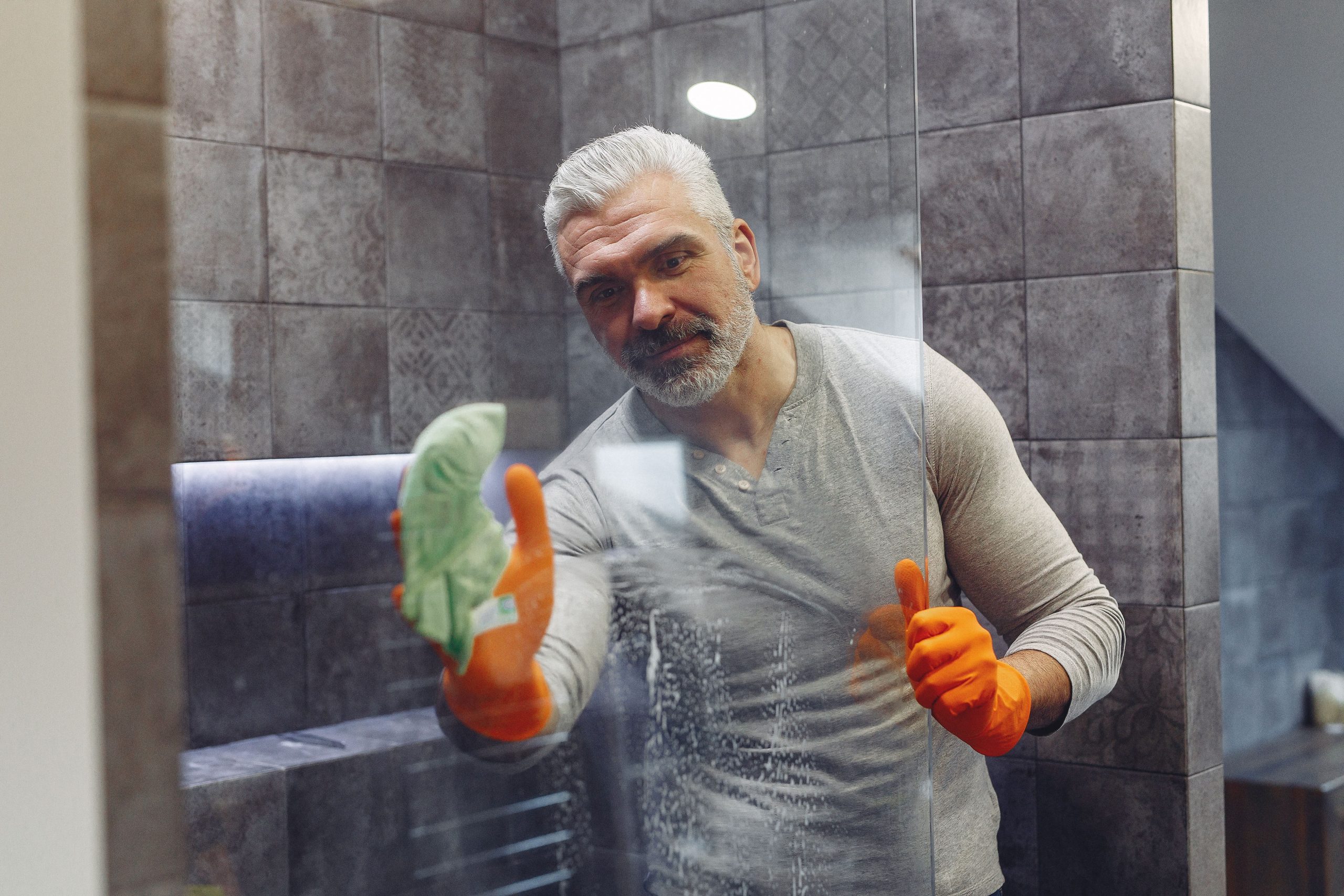 Homme barbu nettoyant paroi douche gants orange