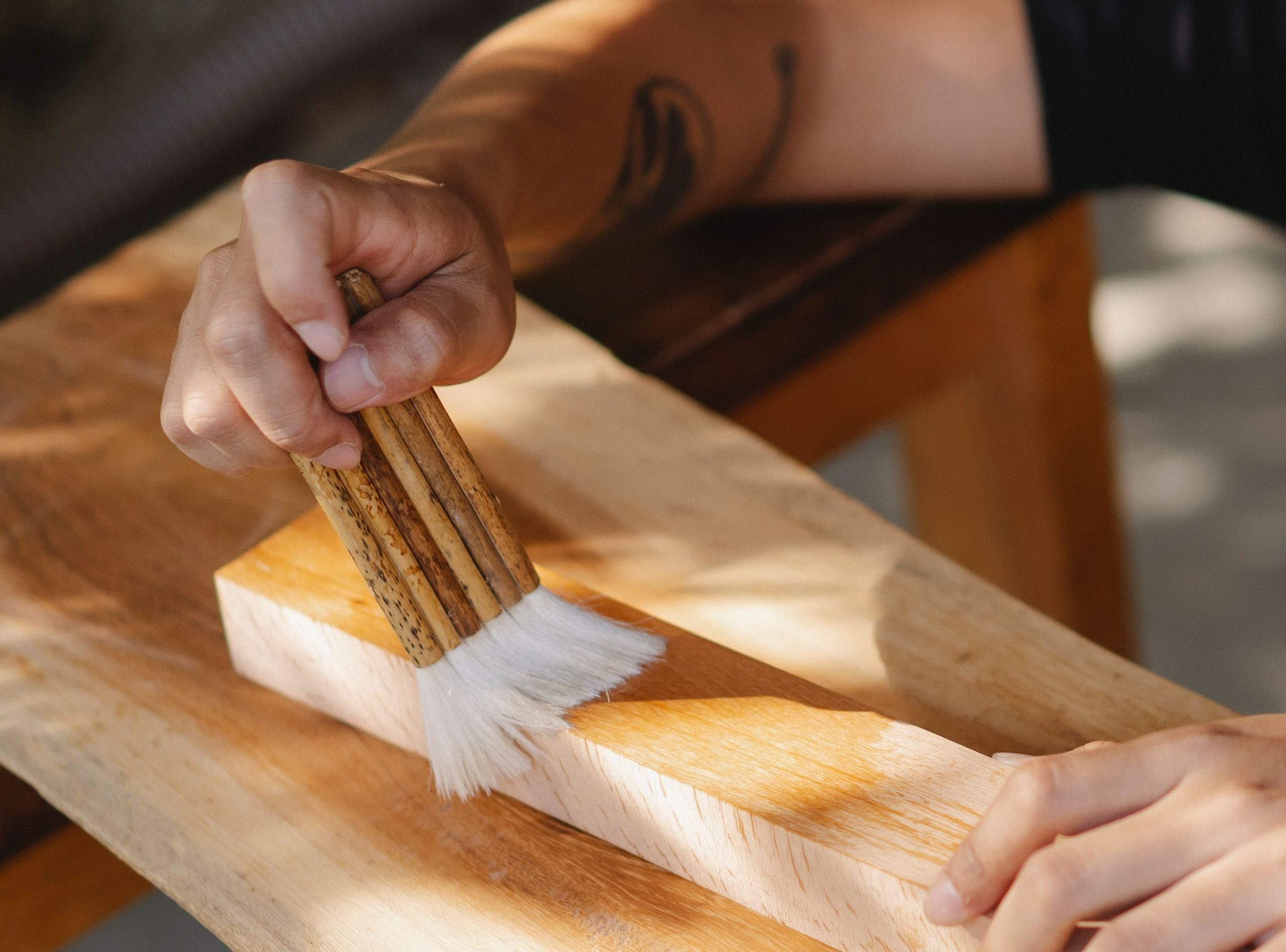Artisan vernissant poutre bois au pinceau